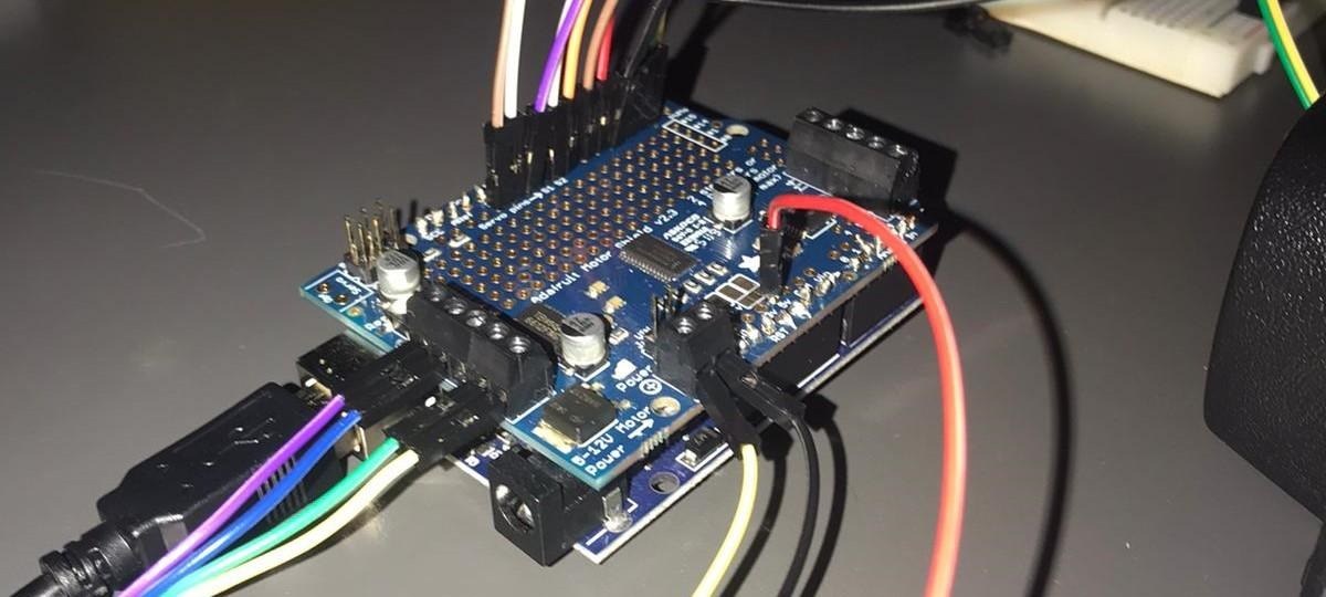 An Arduino UNO with an Adafruit Motor Shield v2.3 stacked on top, wired to a stepper motor and a USB cable