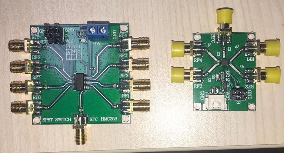 Two green RF switch boards with SMA connectors: an eight-port HMC253 SP8T board on the left and a four-port SP4T board on the right